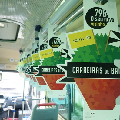 Fotografia de interior de um autocarro onde no balaústre estão pendurantes alusivos às carreiras de bairro 