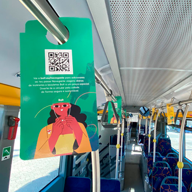 Fotografia do interior de um autocarro com pendurantes nos balaústres alusivos à campanha "Desconto na Bolt para titulares de cartão Lisboa VIVA e passe navegante carregado"