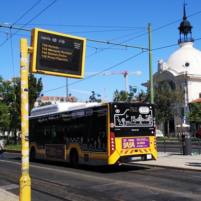 Fotografia de autocarro na Avenida 24 de Julho, em frente ao Mercado da Ribeiro onde aparece um painel de informação dos tempos de espera